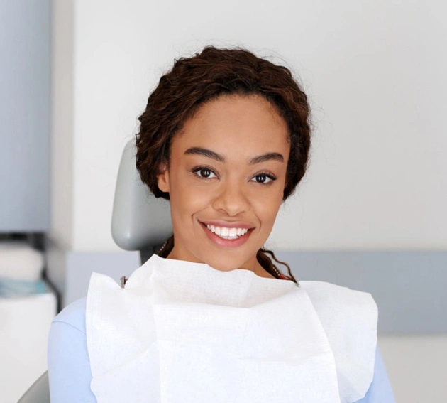 Smiling woman in white medical coat in dental office setting