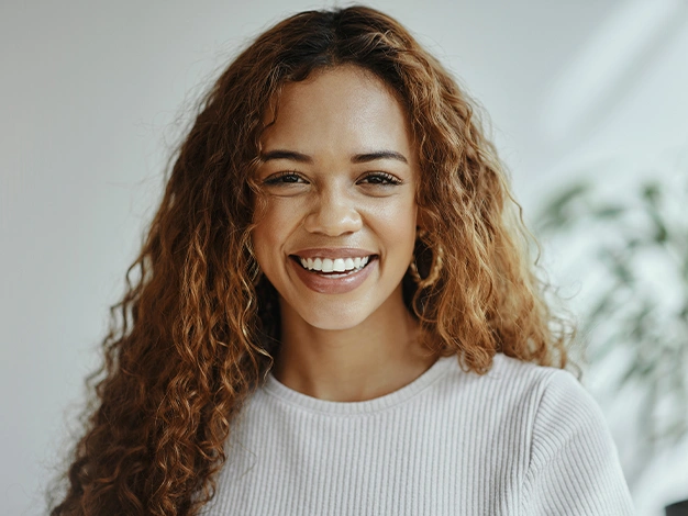 Smiling woman with curly hair in bright dental office setting, representing Maryland Dental Specialty Group